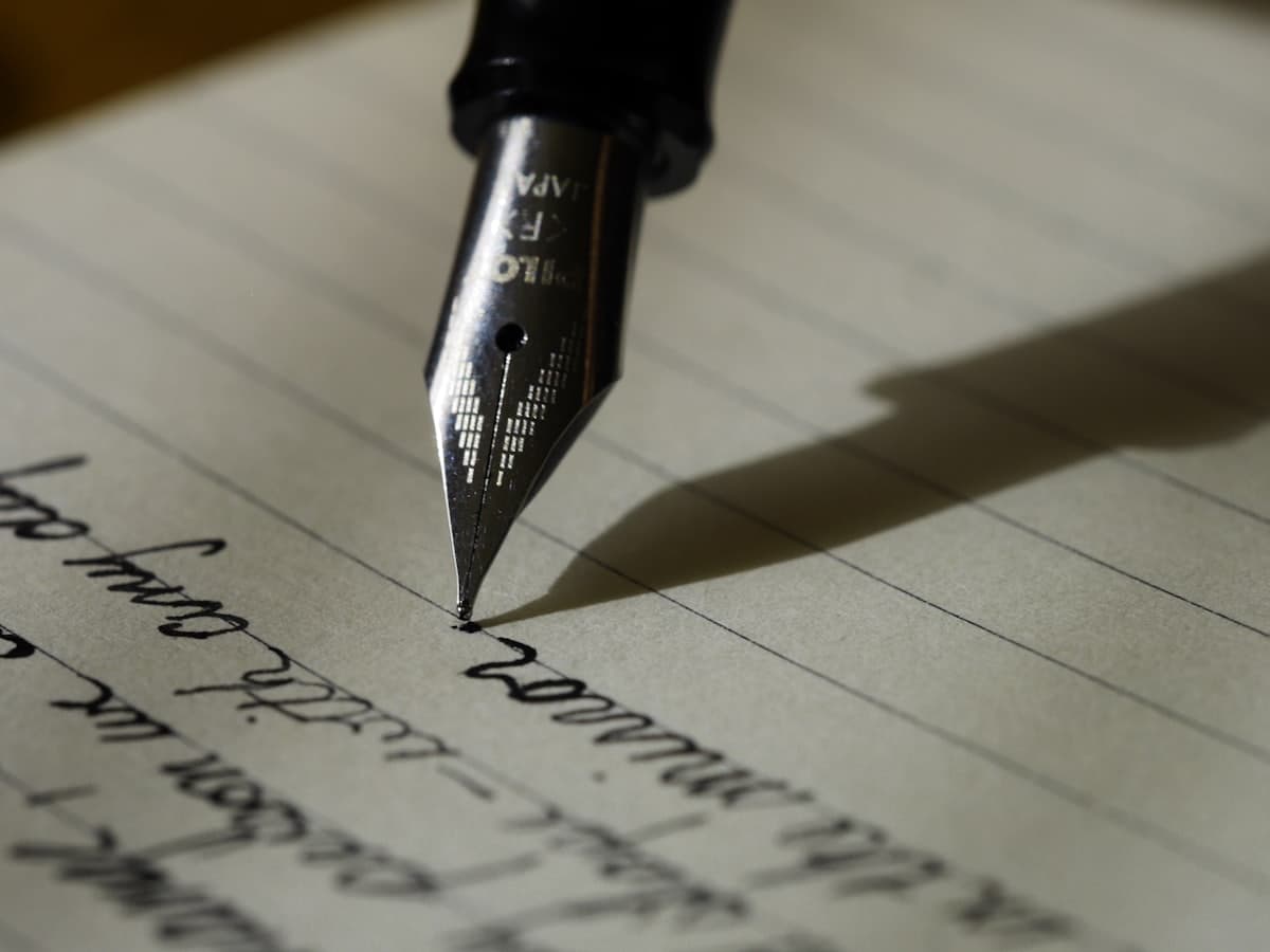 A fountain pen writing a line of text on ruled paper